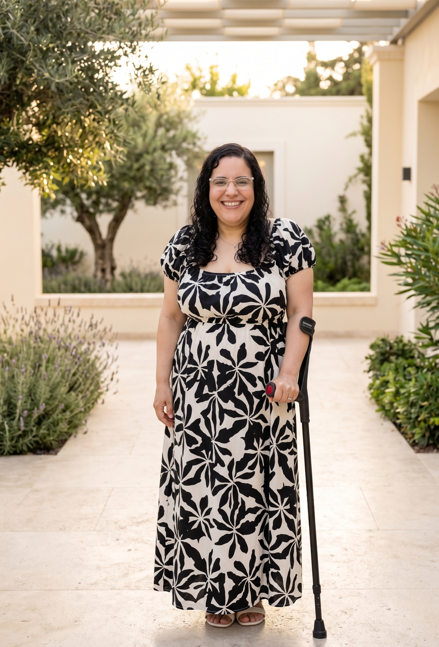 Oriana Zambrano sonriendo de pie con su bastón en un jardín luminoso